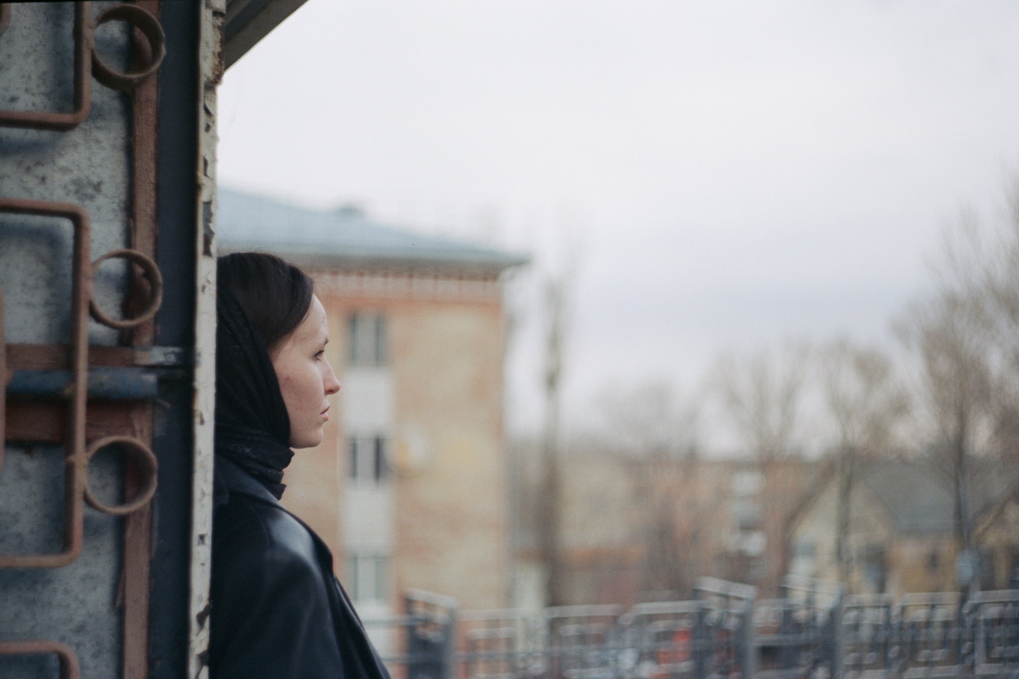 Photo of a woman in black against an old Soviet city shot on a Soviet lens