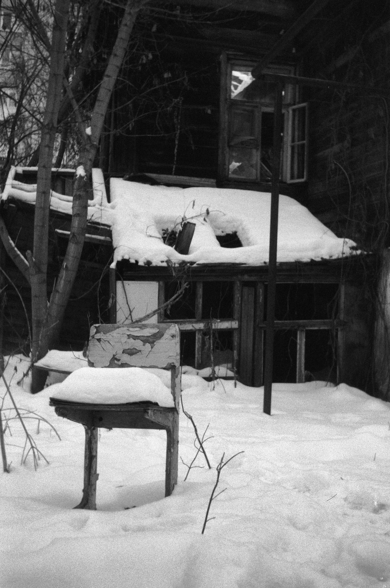 Old chair against a ruined house shot on a soviet film camera