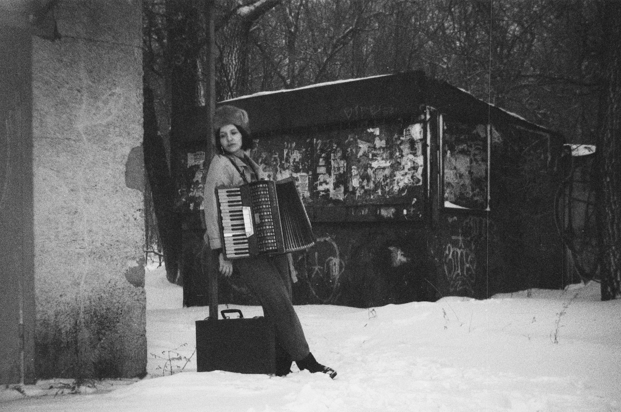 woman with an accordion standing in snow shot on a black and white film